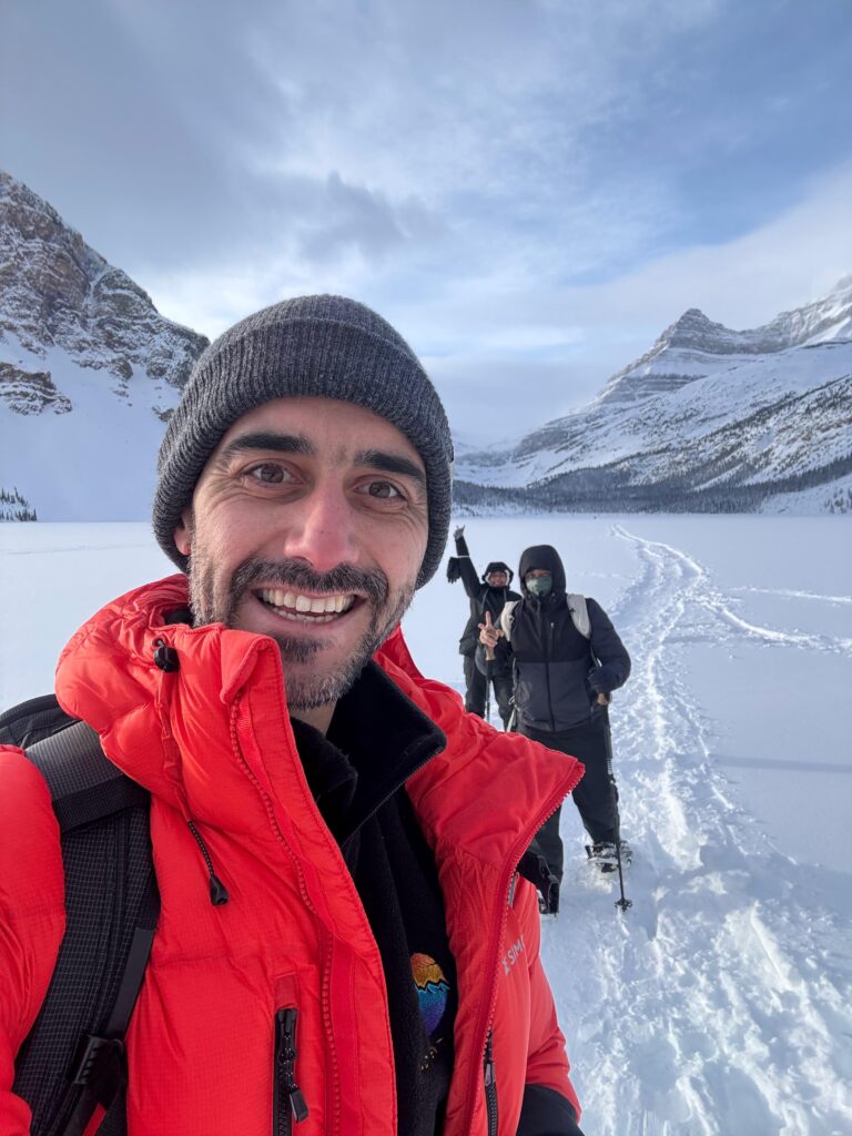 PHOTO-2026-01-05-17-52-07 Local Banff guide, Lyubo, taking a selfie with tour guests on a frozen snow-covered lake in Banff.